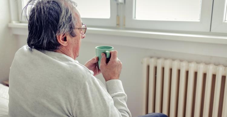 Man with cup of tea looking outside his window